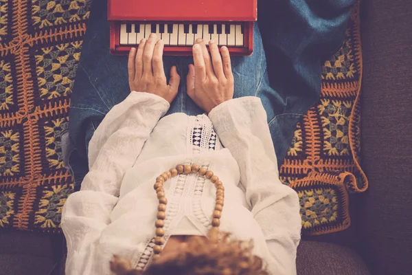 ヒッピー ボヘミアン シックな服を素敵な女の子が再生する少し赤いピアノ音楽玩具 代替生活概念のビンテージの外観のレトロなスタイルのソファの上に座る — ストック写真
