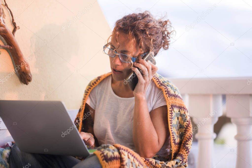 nice woman caucasian in home working at home outdoor in the terrace, speaking at mobile phone connected with team work worldwide. freedom life concept