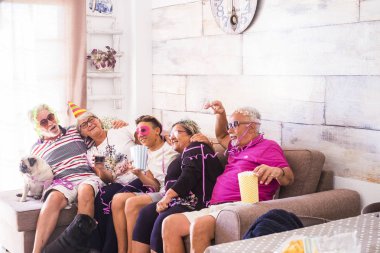 bir grup yaşlı adam beyaz saç, iki erkek, iki kadın, bir çocuk ve iki küçük pugs ile birlikte vakit geçirmek. Oynamak ve gülmek kılık ve renkli maskeleri evde