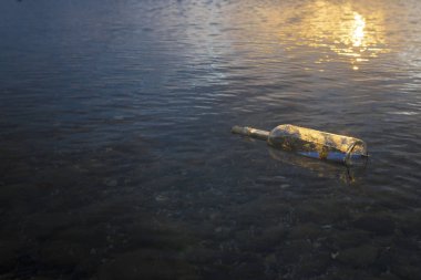şeffaf cam şişe bir mesaj ile deniz tarafından taşınan halat tarafından kapalı ve karaya bir çakıl plajı üzerinde bulundu