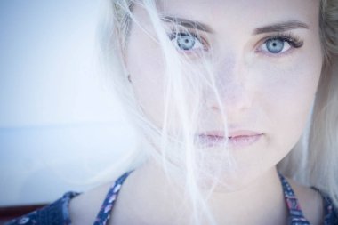 Güzel beyaz beyaz cilt ve mavi gözlü modeli düz şaşırtıcı gözleri seninle seyir poz. sarı saçlı rüzgar tarafından taşındı