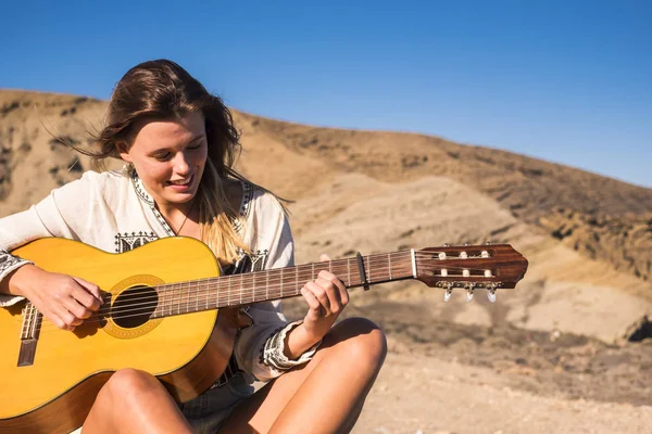 素敵な白人若い女性ギターと屋外に座って歌う山の近きます 自由式と旅行者独立した女の子の概念 — ストック写真