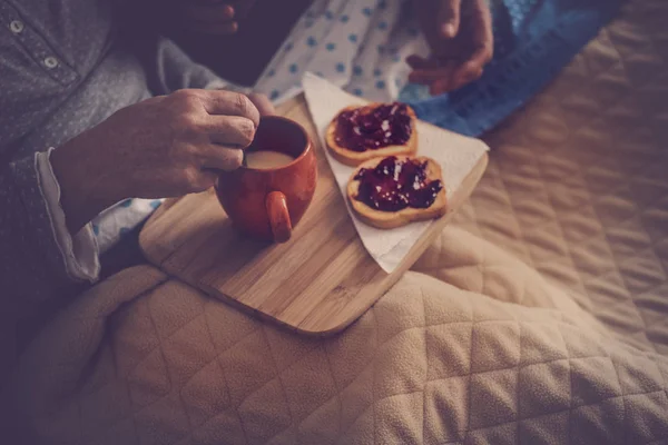 bedroom breakfast close up at home. senior couple eat marmalade and milk and then wake up and start a new nice day together. vintage filter and beautiful light from window