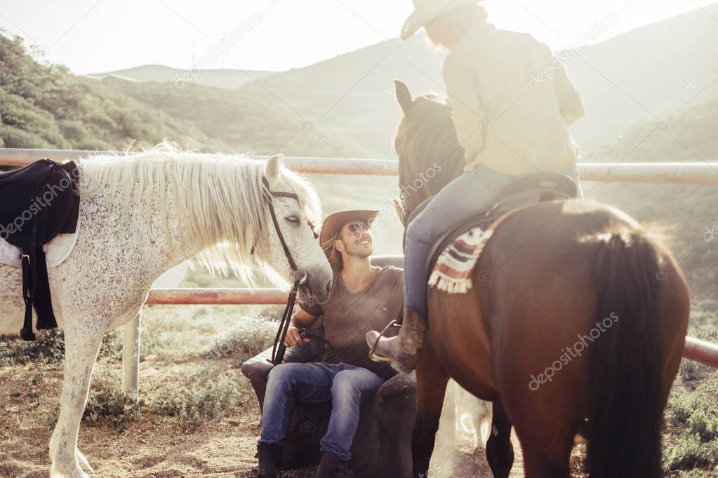 campo y granja de caballos escena diaria con sol y contraluz. dos caballos y dos hombre