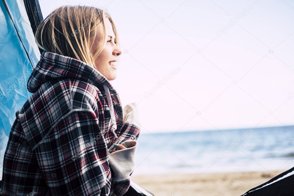 beautiful young blonde woman outside hug herself enjoying freedom and vacation leisure time in the summer. camping free for alternative vacation on the beach near the waves of the ocean