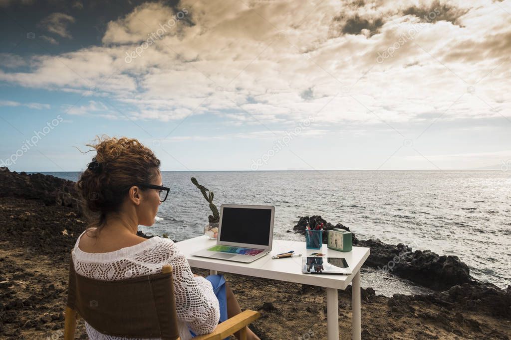 Modern and alternative lifestyle office wokstation with free business woman at work in open office with scenic ocean view