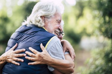 Yaşlı insanlar, yaşlı kakuasyalı çiftler açık hava aktivitelerinde sevgi ve dostlukla kucaklaşırlar.