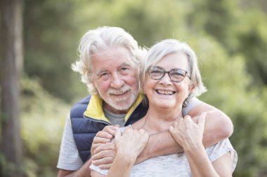 Yaşlı insanlar, yaşlı kakuasyalı çiftler açık hava aktivitelerinde sevgi ve dostlukla kucaklaşırlar.