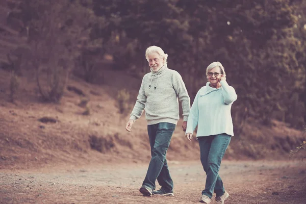 Vintage colors orange tone couple of caucasian senior man and woman walking together in the park having fun