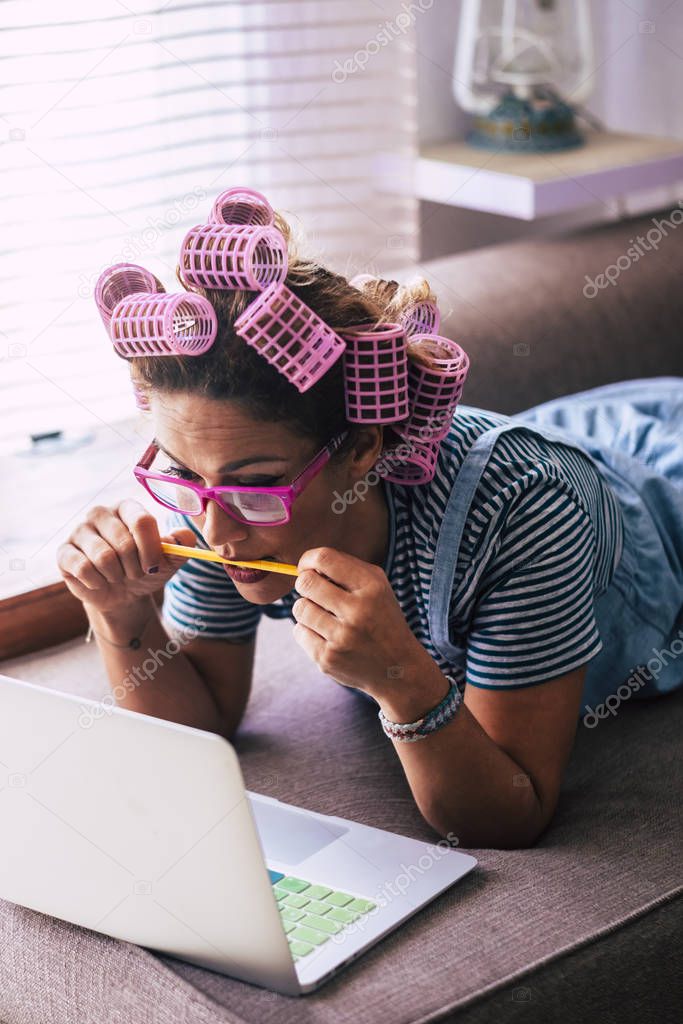 Young pretty trendy caucasian woman at home lay down on the sofa and use modern personal computer laptop 