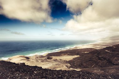 Awesome coastline landscape with ocean blue and mountains with horizon and clouds