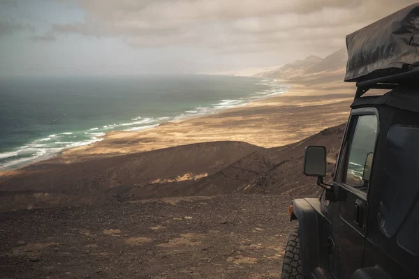 Black off road car with tent on the roof for alternative camping wild vacation concept and wanderlust lifestyle