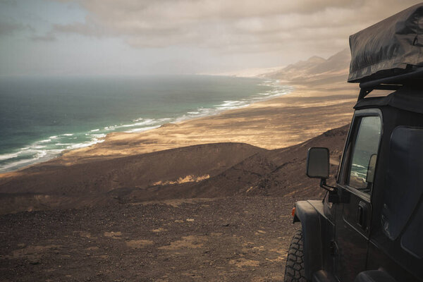 Черный внедорожник с палаткой на крыше для альтернативного кемпинга дикий отдых концепции и образ жизни странствий
 