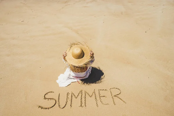 夏とビーチのライフスタイルのコンセプト美しい認識できない女性の空中ビューで地面に書かれた単語の夏と砂の上に座っている — ストック写真