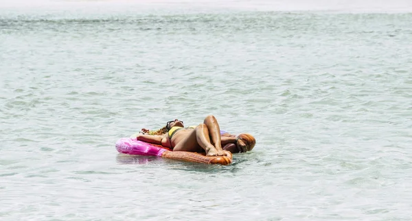 穿着比基尼的快乐而轻松的女人躺在海滩上 享受夏日度假生活中的蓝色透明迷人的水 — 图库照片