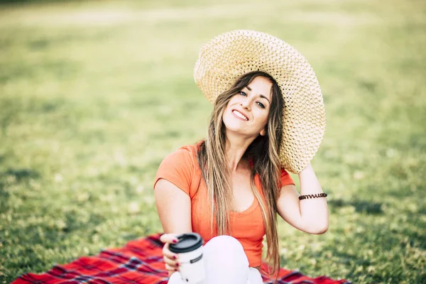 陽気若いです女性とともに帽子と長いですブロンド髪楽しみます屋外レジャー活動下にザ 草の上に座る — ストック写真