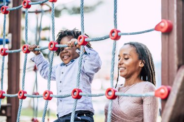 Anne ve küçük çocuk Afrikalı zenci ırk oyun parkında birlikte oynayıp eğleniyorlar ve dışarıda eğleniyorlar.