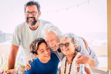 Mutlu üç kuşak aile kucaklaşması ve birlikte eğlenme - insanlar yaşlılar ve gençlerle birlikte grup portresi - parlak gökyüzü geçmişi ve neşeli gülümsemeler