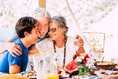 Caucasian people mixed ages and generations - grandfathers and grandson together family at the table eating food and enjoying friendship clipart