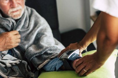 Yaşlı beyaz adam evdeki kan basıncını ölçüyor. Soğuk algınlığı gribi ve koronavirüs acil durumu dünya çapında bulaşıcı bir virüs. 