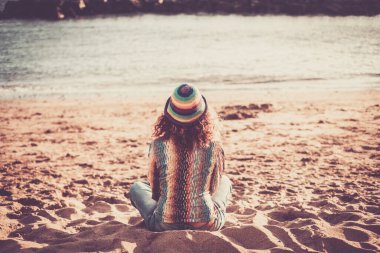 Yalnızlık ve meditasyon, açık hava aktivitesi, modaya uygun bir kadın manzarası, kumsalda oturur, doğaya bakar, hisseder ve okyanusa bakar. 