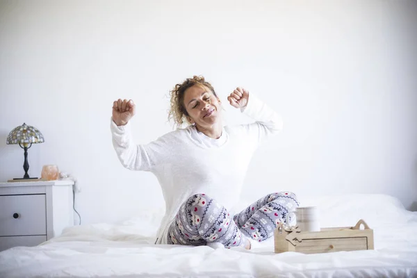Early morning wake up concept with happy cheerful caucasian beautiful adult woman stretching and smiling