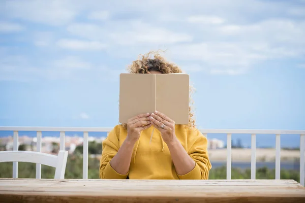 Nerozpoznatelná Žena Číst Papírovou Knihu Venku Dřevěným Stolem Před Modré — Stock fotografie