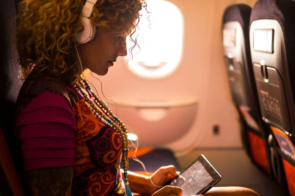 Trendy travel people and beautiful caucasian woman listen music or work inside the aircraft