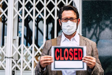 Coronavirus Ekonomik Krizi için dükkanının önünde kapalı tabelası olan yetişkin bir iş adamı. 