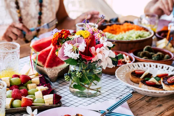 テーブルの近くに食べ物や花の装飾 カラフルな装飾や伝統を食べ 祝う人々のグループのためのベジタリアンランチコンセプトがいっぱいです — ストック写真