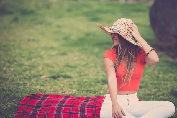 美しいと陽気な若い女の子は赤いシャツで牧草地に座って 一人で屋外の自然レジャー活動を楽しむカバー — ストック写真