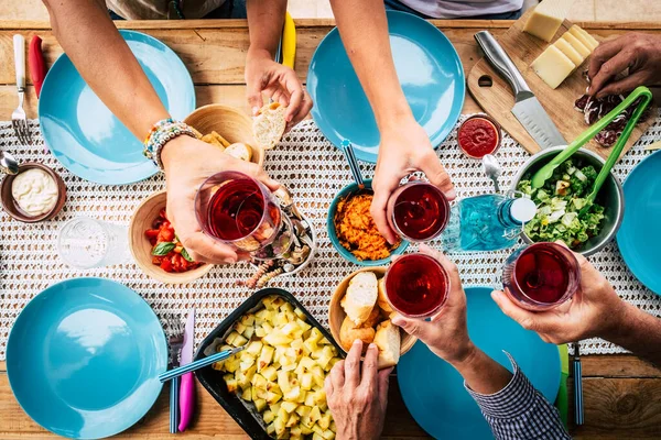 Above view of group of friends people eat and drink together celebrating and having fun toasting with red wine