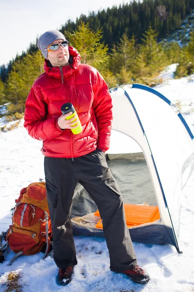 Man met een mok en staat in de buurt van tenten. — Stockfoto