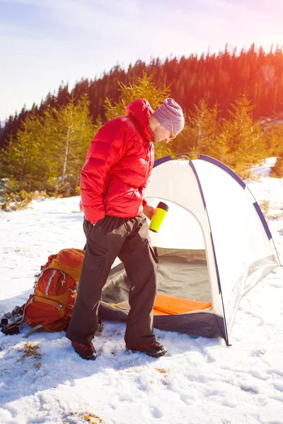 Man med en mugg och står nära tält. — Stockfoto