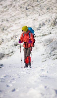 Dağlarda kar üzerinde yürüyen sırt çantası ile kız.