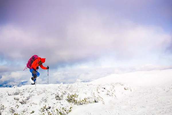 山の雪の上を歩いてのバックパックを持つ少女. — ストック写真