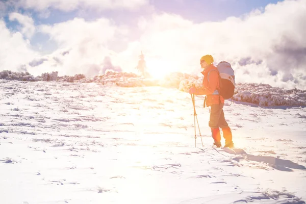 Dívka s batohem chůzi na sněhu v horách. — Stock fotografie
