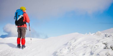 Dağlarda kar üzerinde yürüyen sırt çantası ile kız.