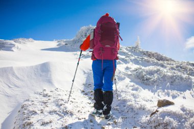 Dağlarda kar üzerinde yürüyen sırt çantası ile kız.