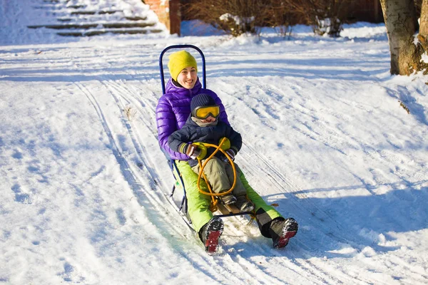 Een moeder met een kind rodelen. — Stockfoto