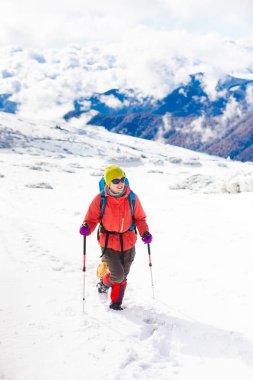 Dağlarda kar üzerinde yürüyen sırt çantası ile kız.