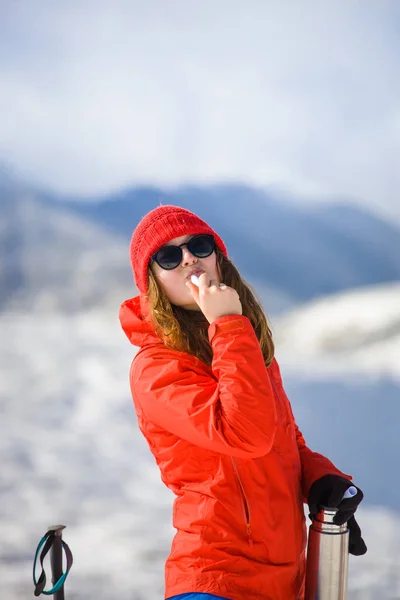 Chica disfruta de un lápiz labial higiénico en las montañas . — Foto de Stock