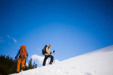Dağcılar kar yamaçta vardır.
