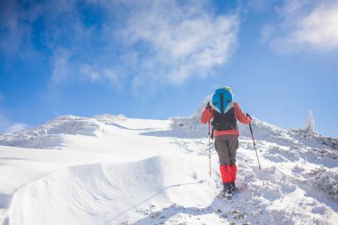 Dağlarda kar üzerinde yürüyen sırt çantası ile kız.