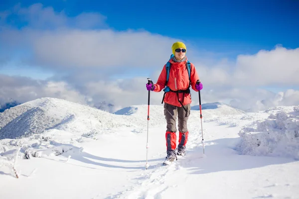 Dívka s batohem chůzi na sněhu v horách. — Stock fotografie
