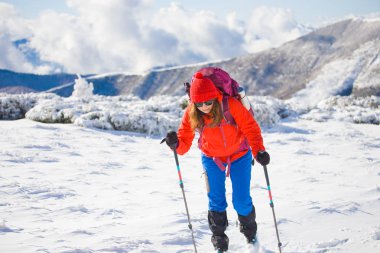 Dağlarda kar üzerinde yürüyen sırt çantası ile kız.