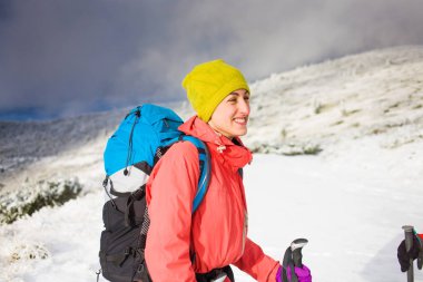 Dağlarda kar üzerinde yürüyen sırt çantası ile kız.