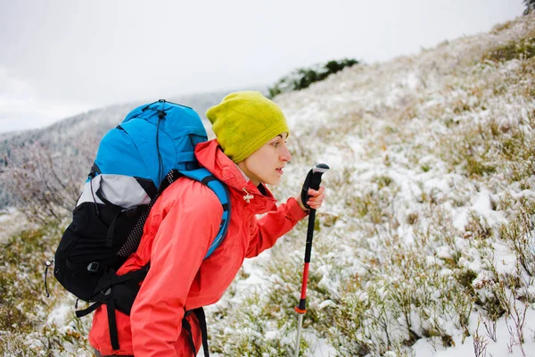Flicka med ryggsäck gå på snö i bergen. — Stockfoto