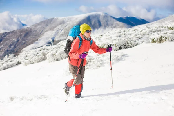 山の雪の上を歩いてのバックパックを持つ少女. — ストック写真