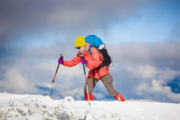 山の雪の上を歩いてのバックパックを持つ少女. — ストック写真